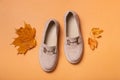 Suede woman's shoes with autumn leaves on orange background.