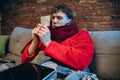 Cropped portrait of young sick boy in warm scarf and gown attentively looking at pills. Medical treatment Royalty Free Stock Photo