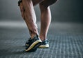 Suffering from a little muscle fatigue. Rearview shot of an unrecognizable young male athlete holding his ankle in pain