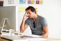 Suffering from writers block. A handsome man sitting at a desk and looking at a computer screen with head rested on his Royalty Free Stock Photo