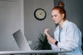 Suffering young redhead business woman having wrist pain during working at laptop computer