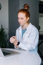 Suffering young redhead business woman having wrist pain during working at laptop computer