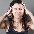 Suffering young woman with hands in her hair having headache