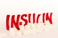 Red cardboard insulin word surrounded by refined sugar cubes on white background, diabetes protection medical concept