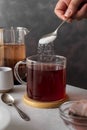 Sugar addiction. Pouring sugar with spoon in cup of tea. Black tea in glass cup. Lifestyle, action drink photo Royalty Free Stock Photo