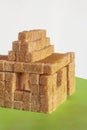 Sugar addition. House formed with brown cane sugar cubes on rough green paper. Sweet home. Concept