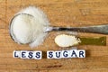 Less sugar advice written with ceramic cubes with letters near the big and small sugar pile. Dieting concept.