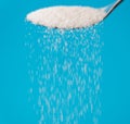 Close up of spoon pouring granulated refine white sugar