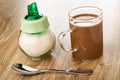 Sugar bowl, cocoa with milk in cup, spoon on wooden table