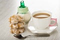 Sugar bowl, stack of gingerbread, coffee with milk in cup on saucer, spoon on table