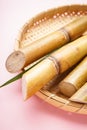 Sugar cane and green leaf in a wooden tray on a pink background, vertically Royalty Free Stock Photo