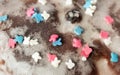 Sugar colored confetti lies on a white icing cupcake, texture of sugar icing on a cupcake surface close-up, pink, blue and white