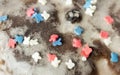 Sugar colored confetti lies on a white icing cupcake, texture of sugar icing on a cupcake surface close-up, pink, blue and white