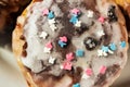 Sugar colored confetti lies on a white icing cupcake, texture of sugar icing on a cupcake surface close-up, pink, blue and white