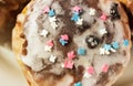 Sugar colored confetti lies on a white icing cupcake, texture of sugar icing on a cupcake surface close-up, pink, blue and white