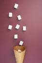 Flying sugar cubes from ice cream cone on red background. Copy space for text. Top view. Royalty Free Stock Photo