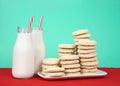 Sugar cookies stacked on plate with bottles of milk