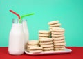 Sugar cookies stacked on plate with two bottles of milk