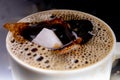 A sugar cube dropped into a cup with black coffee. Falling sugar into a warm drink