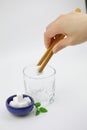 Sugar cubes on a blue plate woman hand hold a wooden tweezers a sugar cube in a glass cup on white background Royalty Free Stock Photo