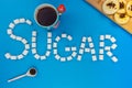 Sugar cubes and cup of black tea and cookies on an isolated blue background making up a word sugar. Royalty Free Stock Photo