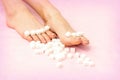 Sugar cubes lying in a row on female feet on pink background with copy space, depilation concept.