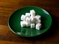 Sugar cubes on a plate and on a wooden table Royalty Free Stock Photo