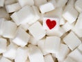 Sugar cubes with a red heart on one of them. Top view. Diet unhealty sweet addiction concept