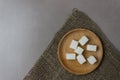 Sugar cubes in a wooden plate on sackcloth on the kitchen table. Top view. With copy space Royalty Free Stock Photo