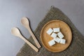 Sugar cubes in a wooden plate with spoons on sackcloth on the kitchen table. Top view Royalty Free Stock Photo