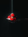 Sugar falls on strawberries on black background, selective focus.Sugar being poured on a strawberry with a dark background