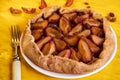 Sugar free pie with plums and raisins on a white plate on yellow wooden background decorated with fresh plums, brown raisins Royalty Free Stock Photo