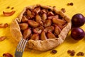 Sugar free pie with plums and raisins on a white plate on yellow wooden background decorated with fresh plums, brown raisins Royalty Free Stock Photo