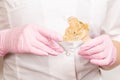 sugar paste for sugaring and depilation on a wooden stick in the hands of a beautician in pink latex gloves