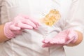 sugar paste for sugaring and depilation on a wooden stick in the hands of a beautician in pink latex gloves