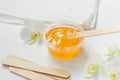 Sugar paste or wax honey in a transparent jar and white orchid on a white background. Sugaring. Depilation and beauty