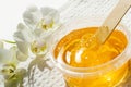 Sugar paste or wax honey in a transparent jar and white orchid on a white background. Sugaring. Depilation and beauty