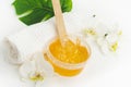 Sugar paste or wax honey in a transparent jar and white orchid on a white background. Sugaring. Depilation and beauty
