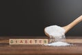 Sugar poured on a wooden table with DIABETES word.