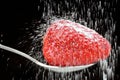 Sugar powder pour on a strawberry in a spoon on black background