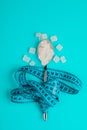 Sugar-replacing tablets or sugar with a spoon are entangled in the measuring tape. On a blue background. The concept of diabetes Royalty Free Stock Photo