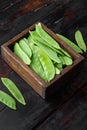 Sugar snap peas, raw ripe baby pods, in wooden box, on old dark wooden table background