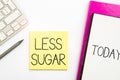 LESS SUGAR text written on a notepad surrounded with some office supplies