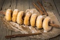 Sugared mini donuts lined up on a cinnamon stick on a wooden table