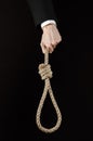 Suicide and business topic: Hand of a businessman in a black jacket holding a loop of rope for hanging on black isolated