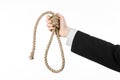 Suicide and business topic: Hand of a businessman in a black jacket holding a loop of rope for hanging on white isolated