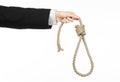 Suicide and business topic: Hand of a businessman in a black jacket holding a loop of rope for hanging on white isolated Royalty Free Stock Photo