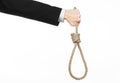 Suicide and business topic: Hand of a businessman in a black jacket holding a loop of rope for hanging on white isolated