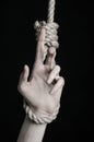 Suicide and depression topic: human hand hanging on rope loop on a black background Royalty Free Stock Photo