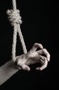 Suicide and depression topic: human hand hanging on rope loop on a black background Royalty Free Stock Photo